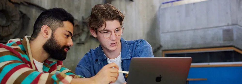 Two people looking at a laptop.