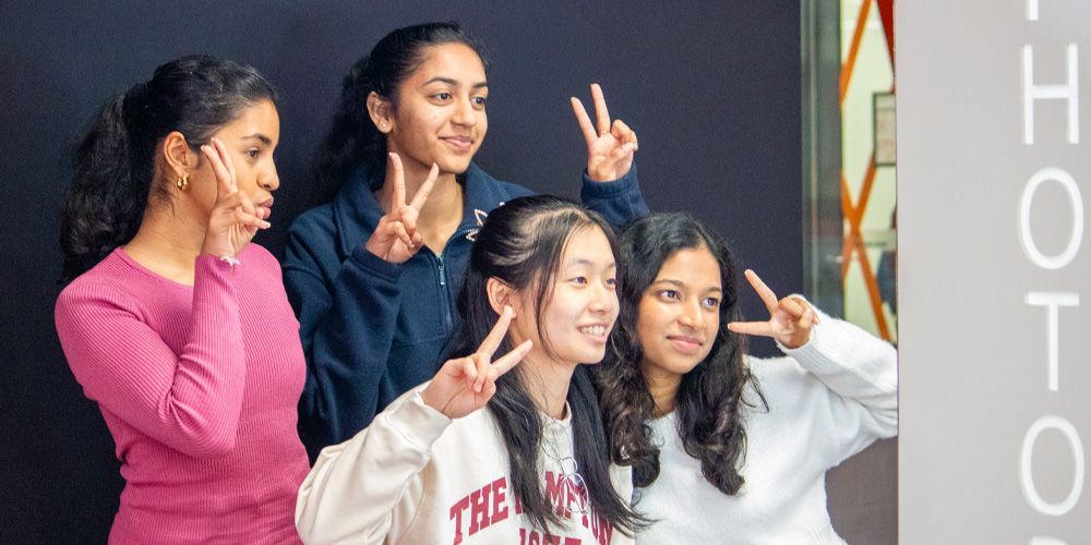 Four students posing in front of a photobooth camera