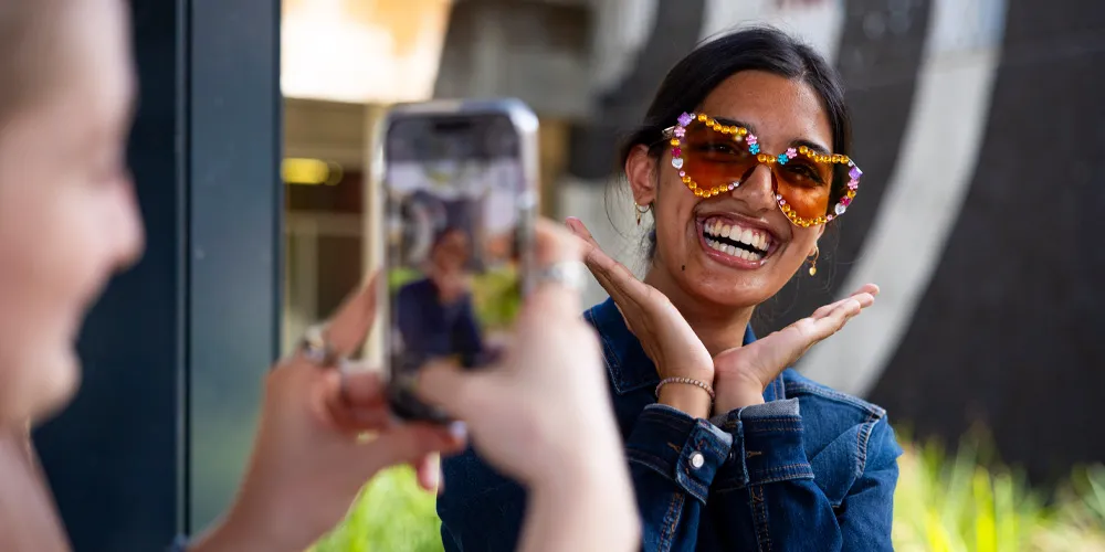 A person wearing jewel-covered sunglasses and smiling.