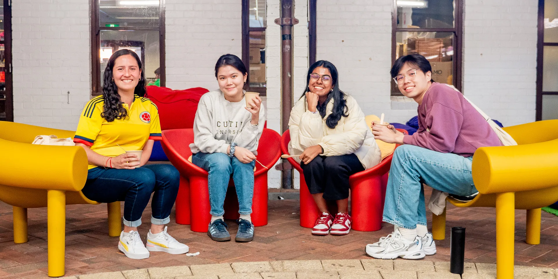 A group of students sitting on chairs and smiling at the camera.