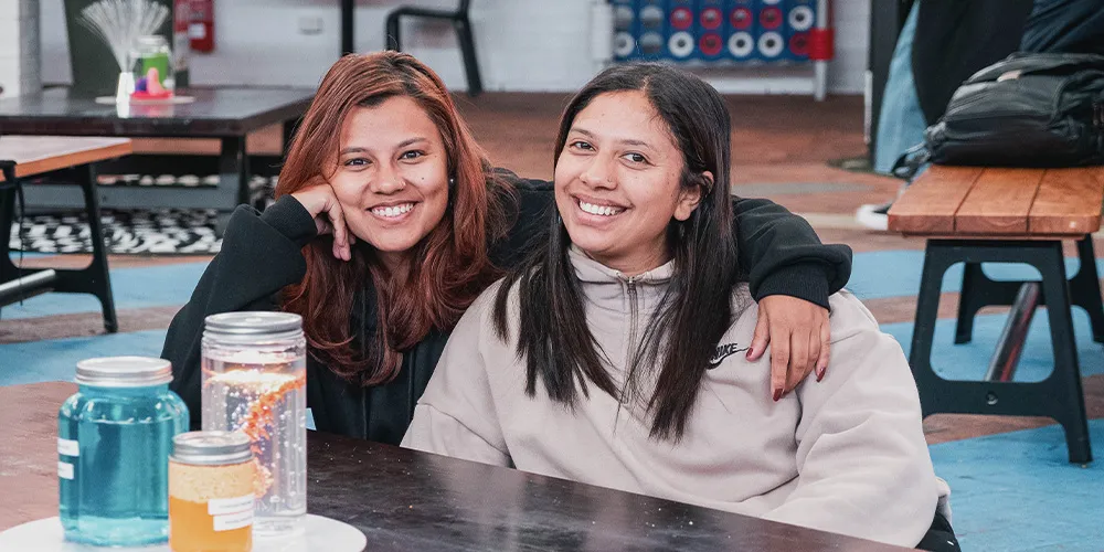 Two students sitting together at the O-Week hub.