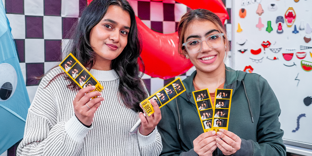 Two people holding photo booth film strips.