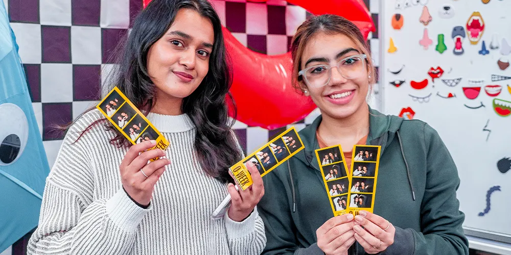 Two people holding photo booth film strips.