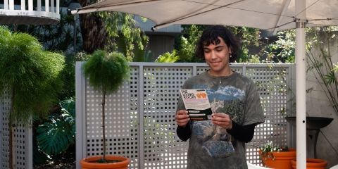 A student reading a leaflet about The Living Room in an outside garden