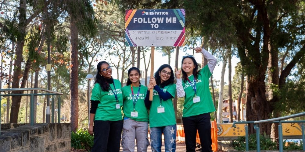 Four Curtin mentors holding up a sign that reads 'Follow me'