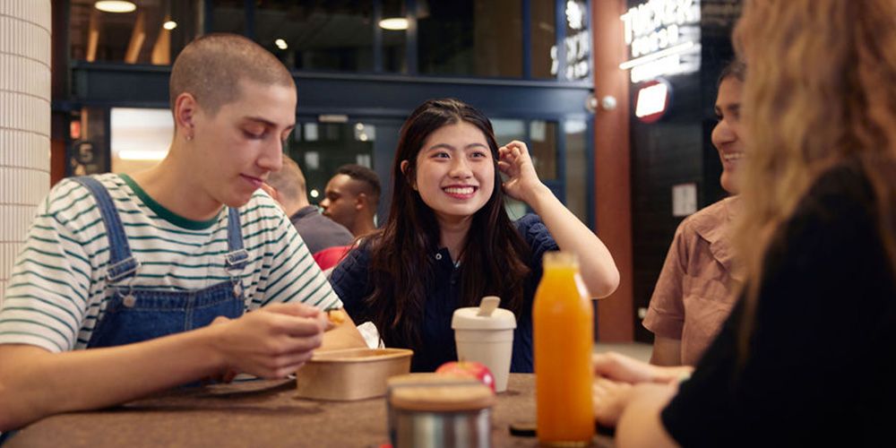Group of students sitting down together eating