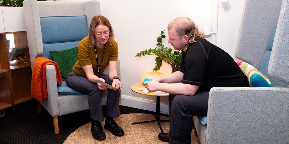 A peer support advisor talking to a student in the Living Room.