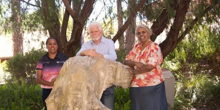 Three people stood outside with trees in the background