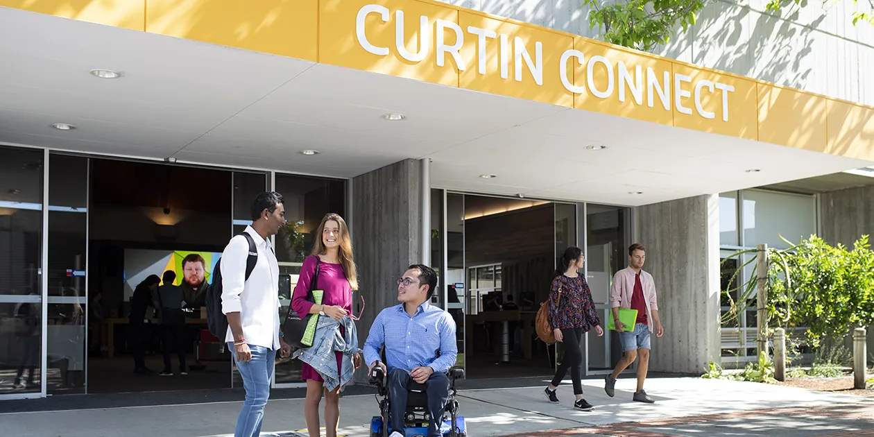 Two students standing and another student in a wheelchair out the front of Curtin Connect, talking