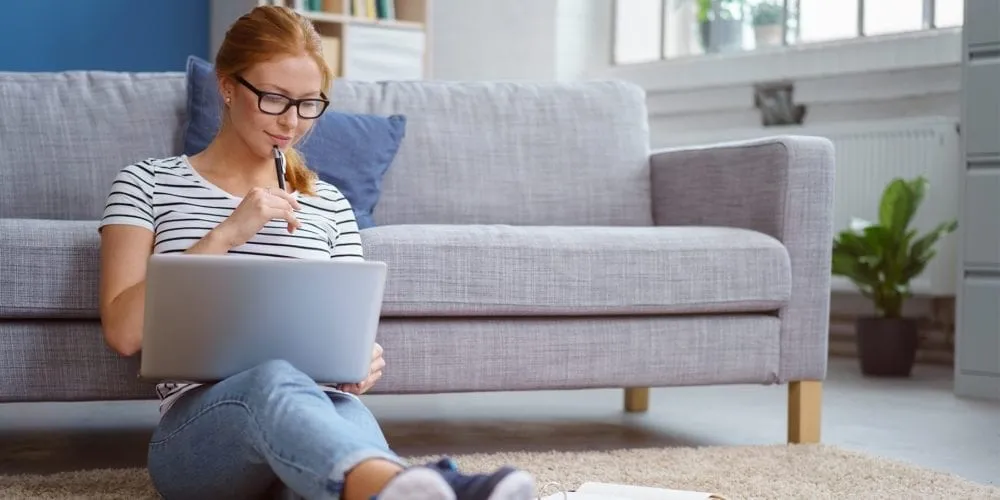 Female student studying on lounge floor with laptop