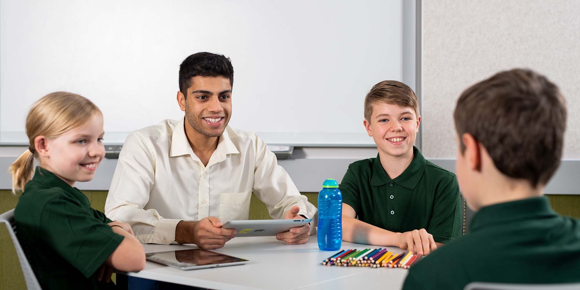Teacher sitting at a desk with three students