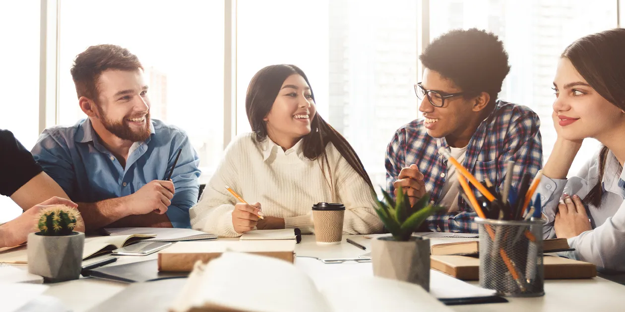 Four students studying and smiling at each other.