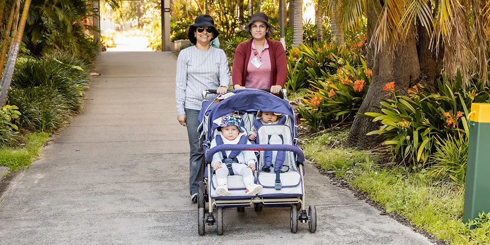 Two women pushing children in prams