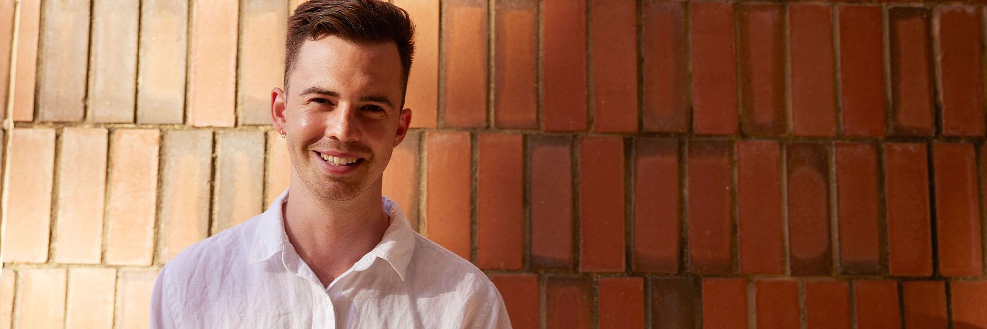 Smiling student in front of brick wall