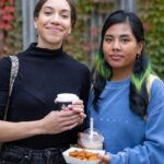 Two students with food and drinks from the food trucks