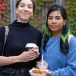 Two students with food and drinks from the food trucks