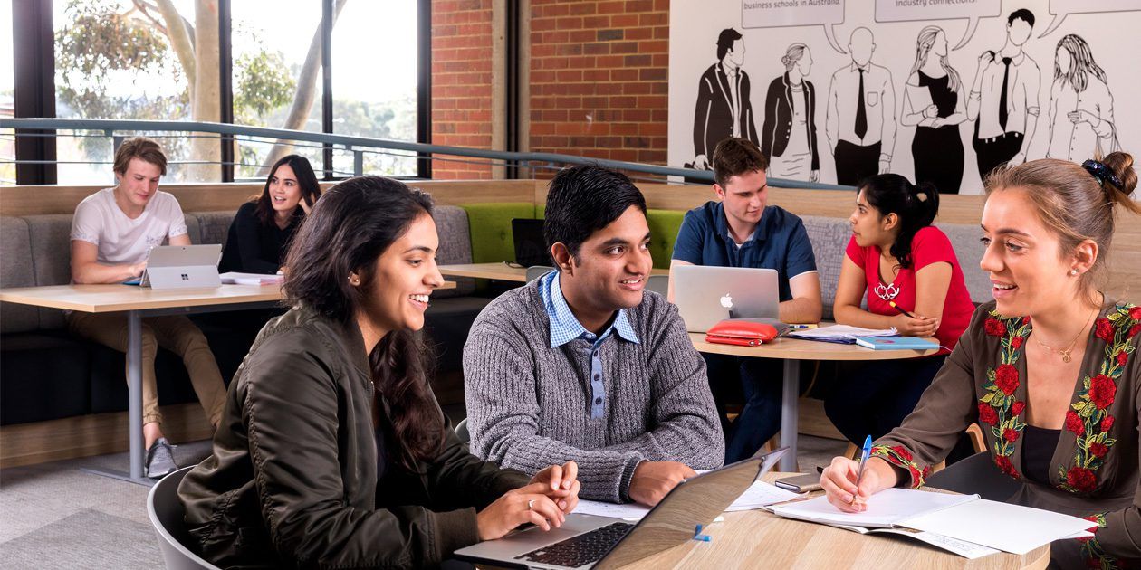 Three Curtin business students in a class room setting having a discussion