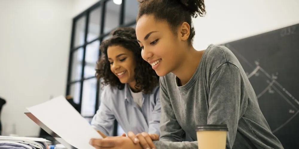 Two female design students reviewing study notes together