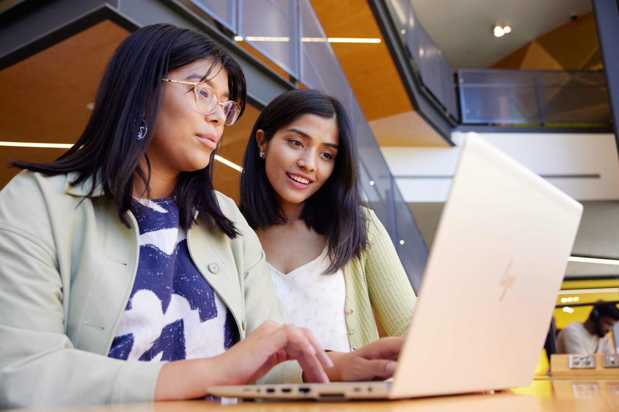 Female students at campus, looking at laptop