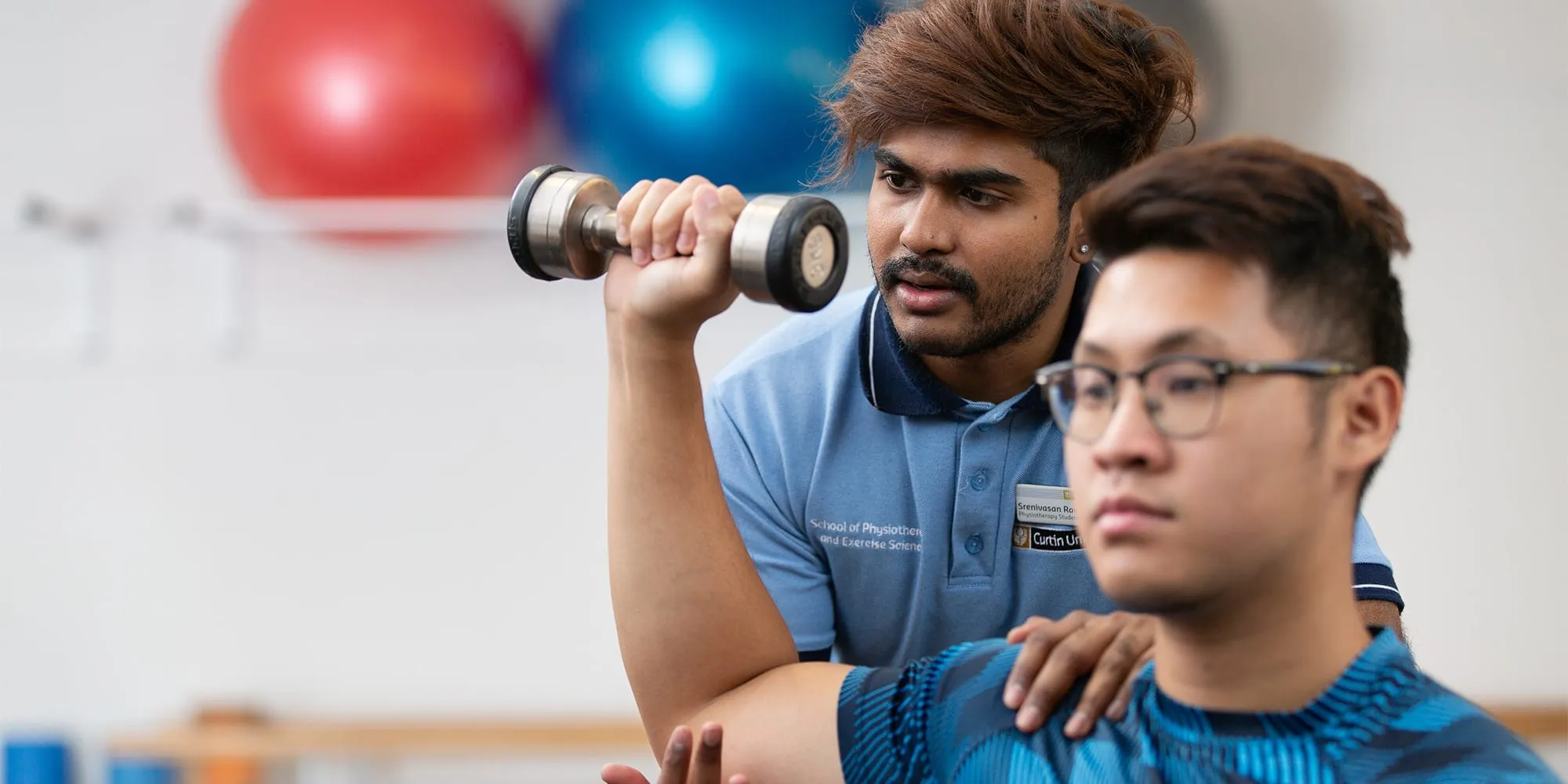 Physiotherapy student assisting a client with free weights exercises