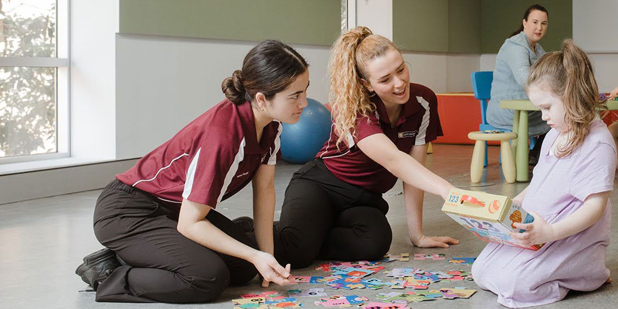Two health sciences students in a clinical setting with a young child