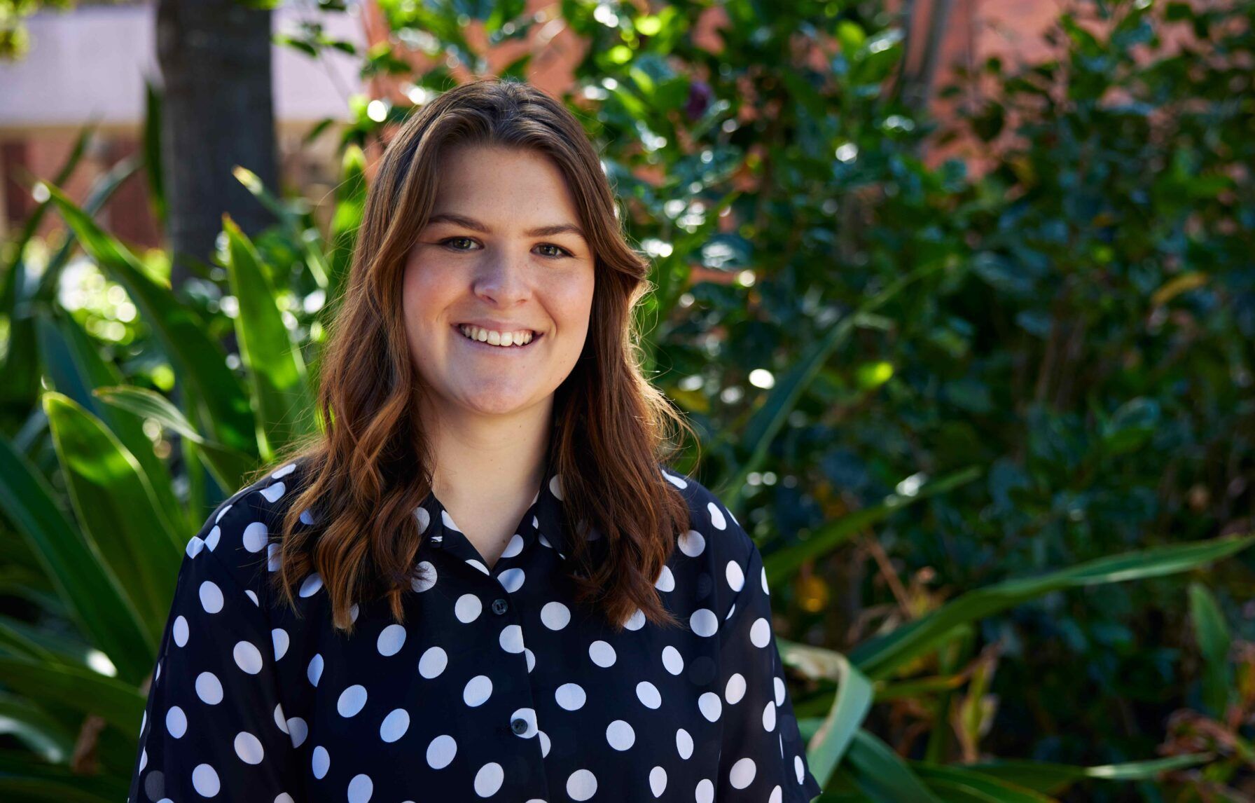 student smiling in front of plants