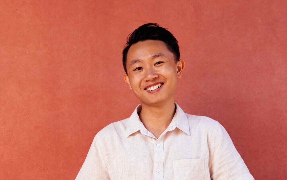 A male student on campus in front of an orange wall