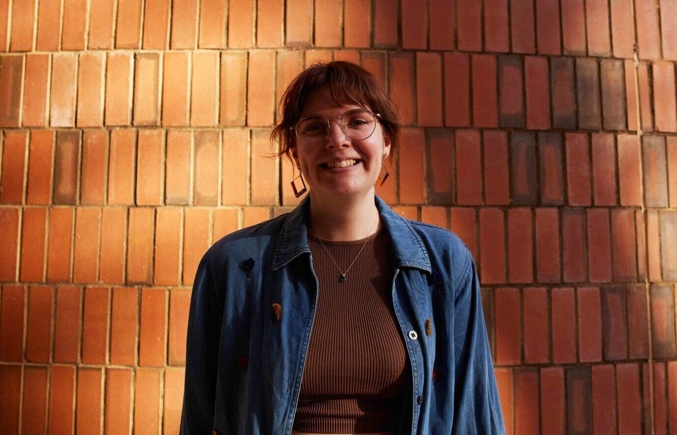 student smiling in front of brick wall