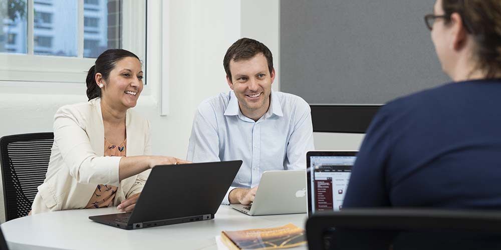 Business students collaborating around a laptop