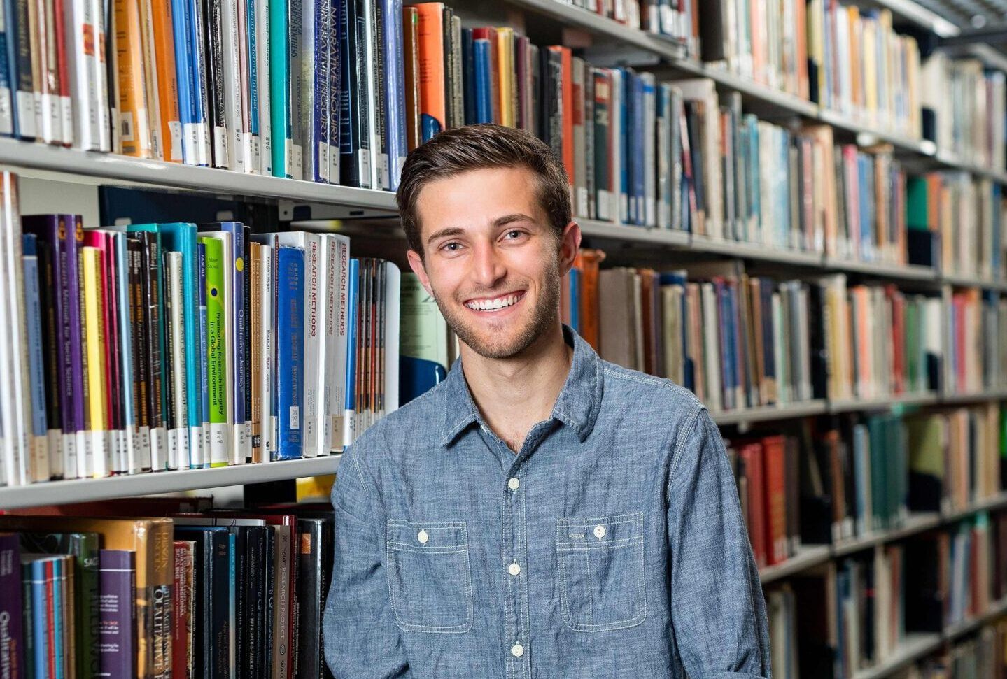 student smiling in front of bookshelf