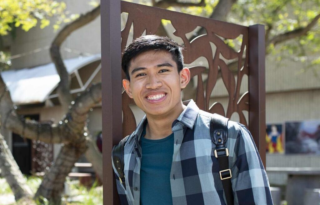 student smiling in front of garden