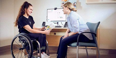 Two women speakign with each other, one sitting in a wheel chair