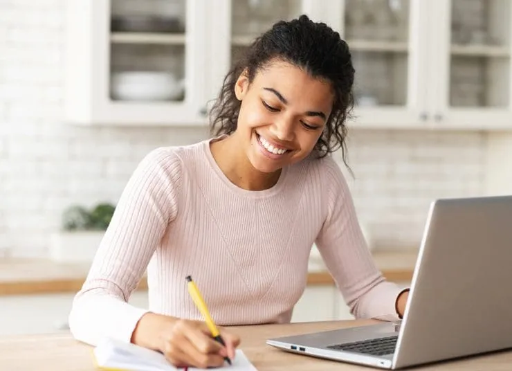 Student smiling and writing on paper
