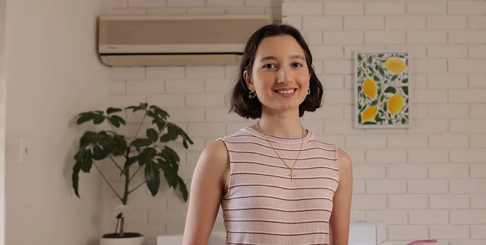 Female Commerce student Mary standing in an kitchen setting