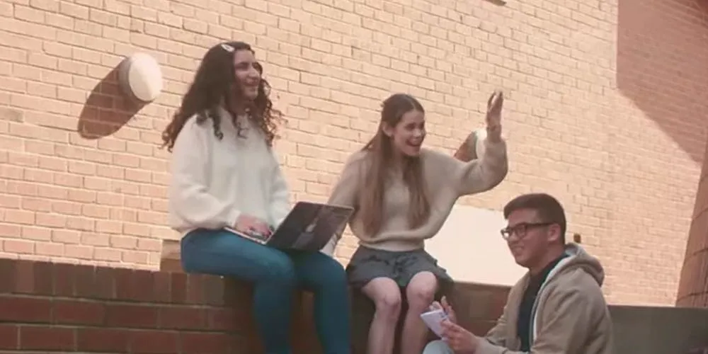 Group of students sitting on a wall - play video