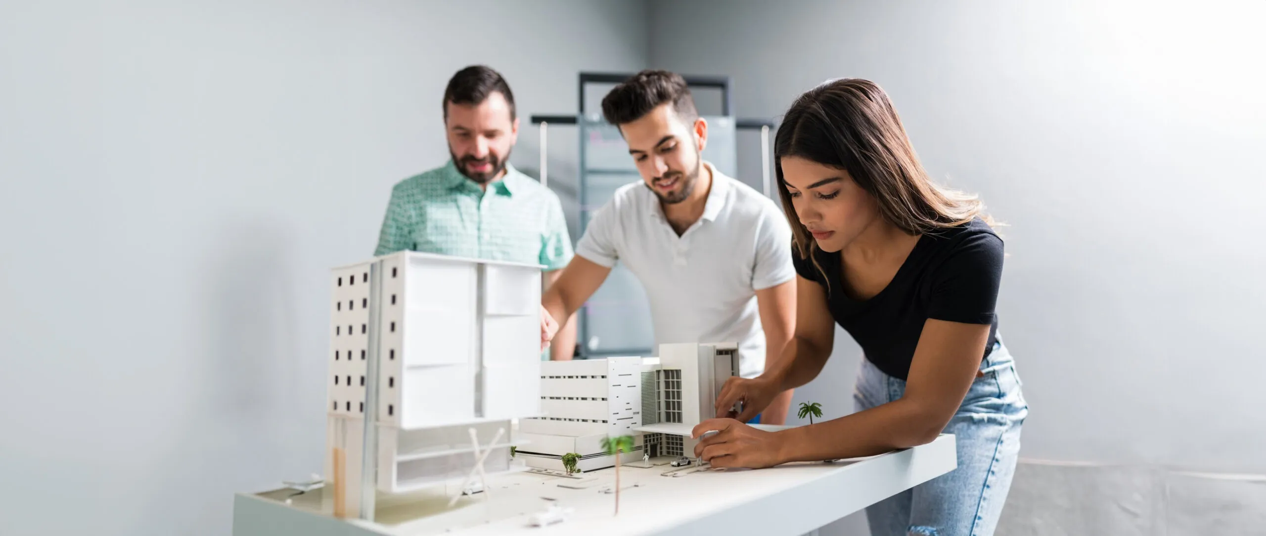 Female architect communicating with coworkers over a model building