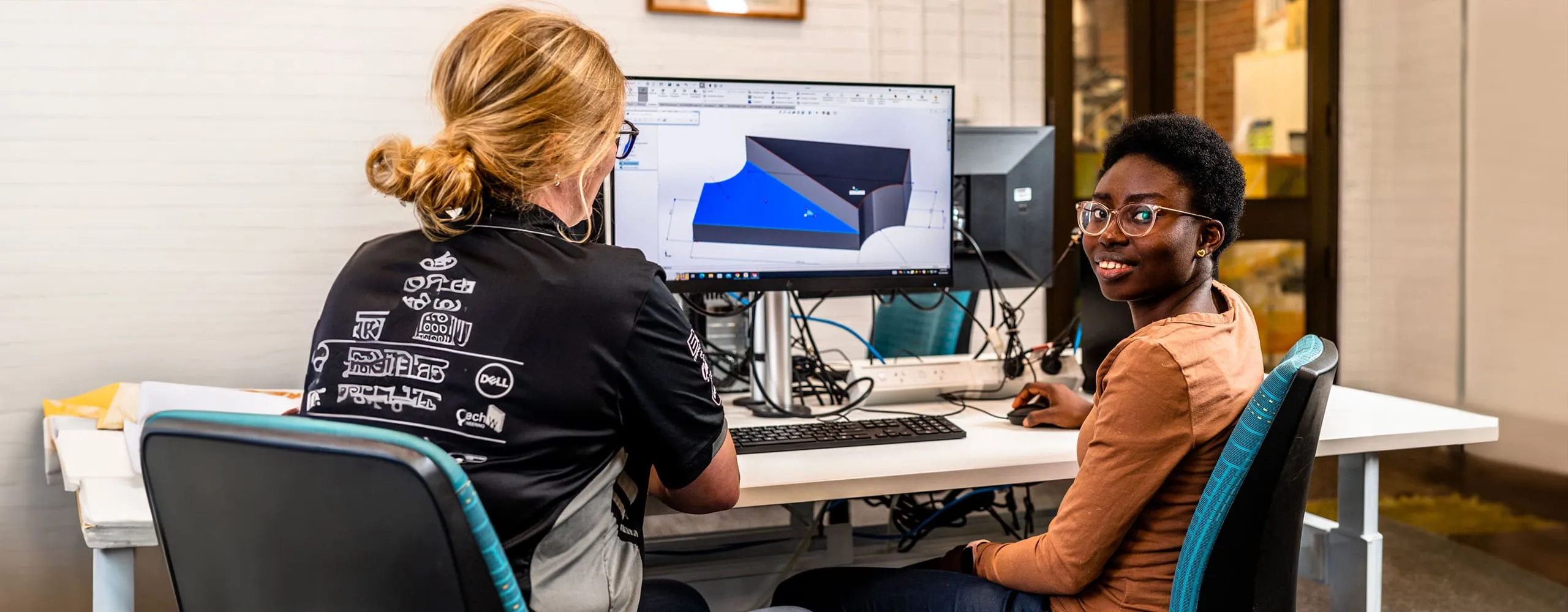 Two female students in front of a computer displaying an engineering program
