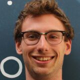 Curtin Science student Daniel Werndly standing against a blue background with white circles on it