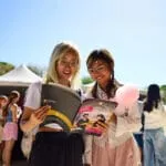 Two young students are discussing the content of a course brochure as they review it together.