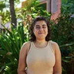 Female student with dark curly hair in front of lush plants