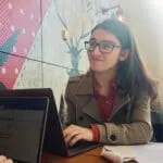Young male student with long hair, wearing glasses and typing