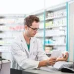 Pharmacy student comparing leaflet with medication