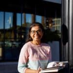 Young, happy student wearing glasses, standing outside the Curtin library