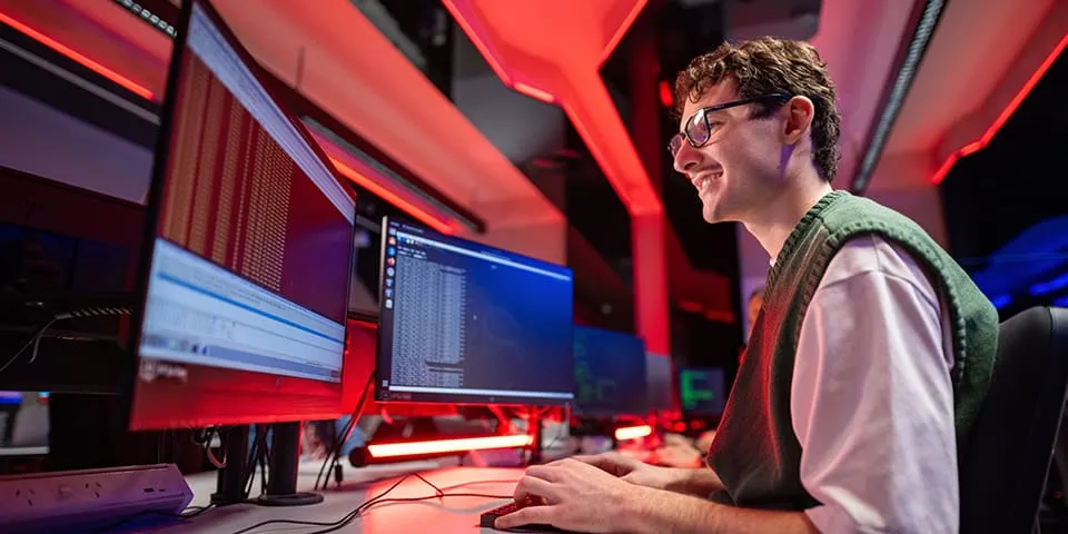 Male Cyber Security student working at a desk
