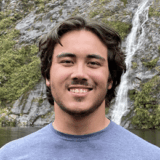 Advanced Biomedical Sciences student smiling to camera with greenery in the background.