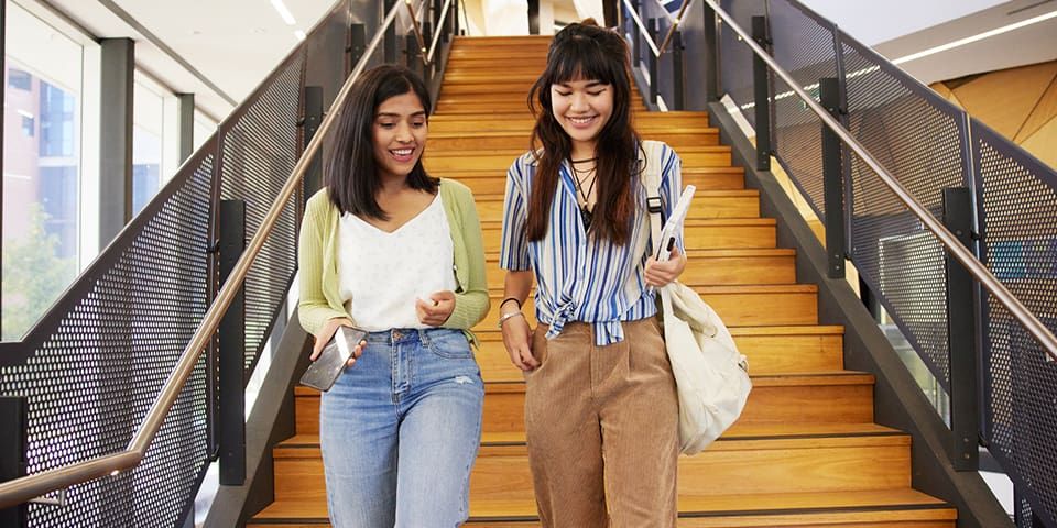 Two students walking down the stairs at Curtin Library