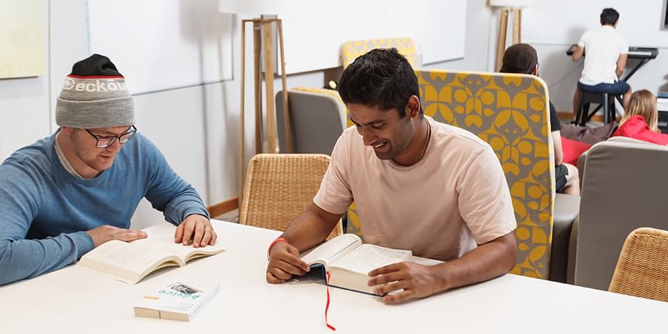 Students sitting at a table and reading at the Erica Underwood House