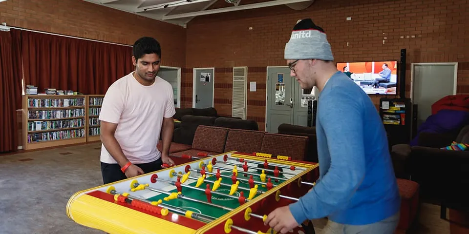 Two students playing a game of foosball at Vickery House