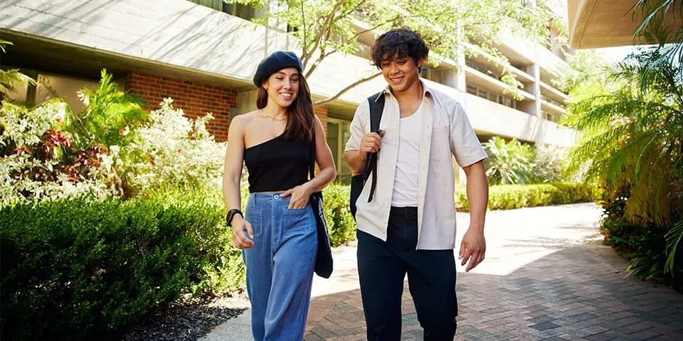 Two students walking in between buildings on Curtin campus.