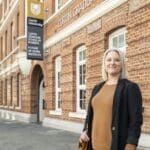 A Master of Business Administration (MBA) student standing in front of the Curtin Graduate School of Business.
